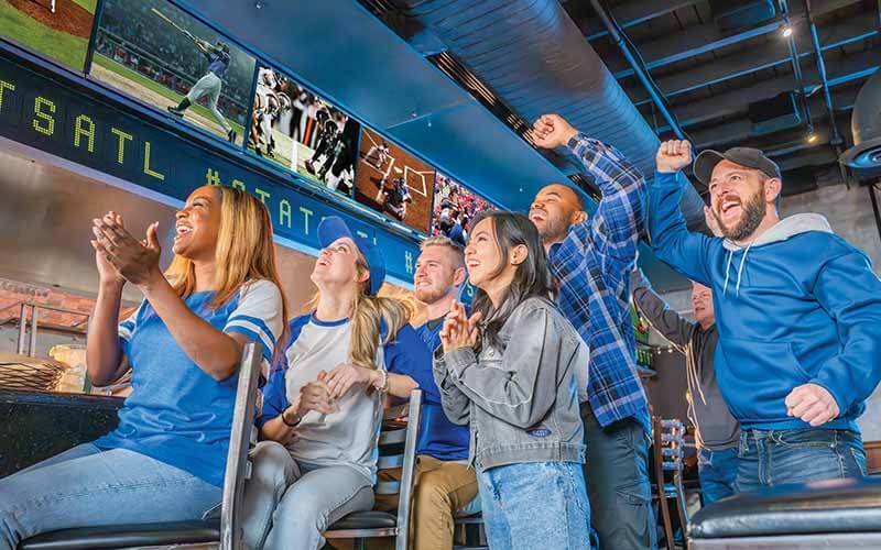People being served in restaurant with sports on TV